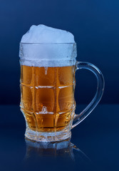 Glass beer mug with foam isolated on dark background.