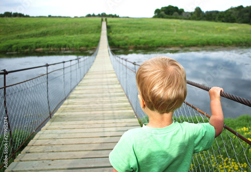Fotografía Cute toddler boy on a suspension bridge across the river