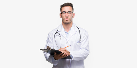 Sticker - Handsome young doctor man holding a clipboard with a confident expression on smart face thinking serious