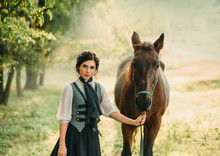 A Young Lady In A Vintage Dress Strolls Through The Forest With Her Horse. The Girl Has A White Blouse, A Jabot, A Tie, A Gray Vest, A Black Long Skirt With A Train. An Ancient, Collected Hairstyle