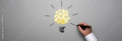 Cuadros en Lienzo Wide panorama view of puzzle pieces and male hand drawing light bulb