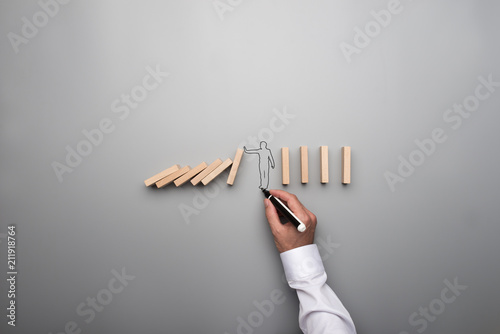Fotografía Man drawing the outline of a businessman stopping the domino effect