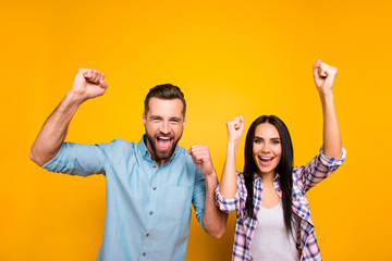 Poster - Portrait of joyful lucky couple with raised arms celebrating victory of football team yelling loudly isolated on vivid yellow background