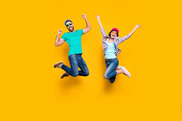 portrait of lucky successful couple jumping with raised fists celebrating victory wearing denim outf