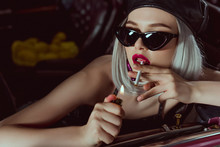 Sensual Young Blonde Woman In Beret And Sunglasses Smoking Cigarette In Car