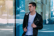 © Skripnik Olga - young, beautiful and attractive guy is standing near the glass building the city, posing.