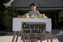 Boy With Homemade Grapefruit Stall On Driveway