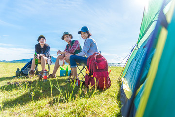 group of travelers camping and doing picnic in meadow with tent foreground. mountain and lake backgr
