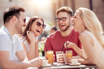 Poster - Four laughing friends enjoying coffee in a cafe