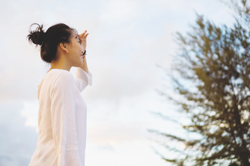 Young woman looking far away in a park during sunset.