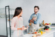 girlfriend grating cheese and handsome boyfriend drinking wine in kitchen
