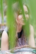 © Anna Jurkovska - Portrait of a young beautiful woman sitting at a table in a pavilion among ornamental plants