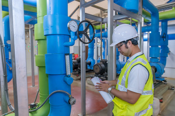Wall Mural - Asian engineer wearing glasses working in the boiler room,maintenance checking technical data of heating system equipment,Thailand people