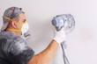 © Patryk Kosmider - Plasterer wearing dust mask polishes a wall with sanding machine . House renovation concept.