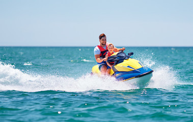 Wall Mural - happy, excited family, father and son having fun on jet ski at summer vacation