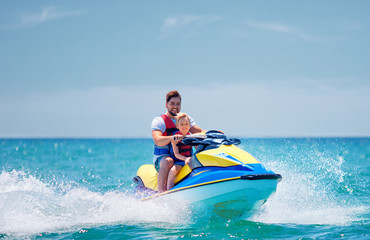 Wall Mural - happy, excited family, father and son having fun on jet ski at summer vacation