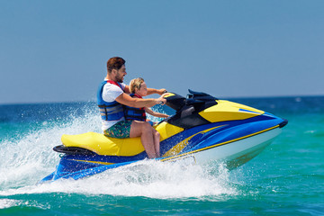 Wall Mural - happy, excited family, father and son having fun on jet ski at summer vacation