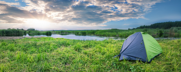Wall Mural - green and gray tourist tent on the river bank in summer