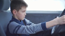 Boy Sitting Behind The Wheel Inside The Car