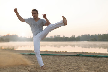 Wall Mural - Athletic capoeira performer workout training on the beach sunris