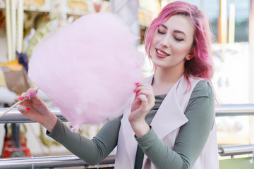 Portrait of pretty with pink hair girl with short haircut posing in amusement park on carousel background. female with pink ombre hair with sequins photodyeing hair curls bright glitter fashion