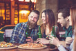 © davit85 - Friends having a drinks in a bar, They are sitting at a wooden table with beers and pizza.