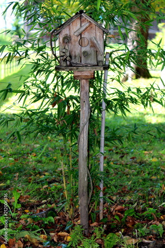 Fotografia, Obraz Old aged vintage wooden bird house situated on top of wooden spike and supported