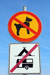 No dogs allowed and no camping allowed signs on clear blue sky background