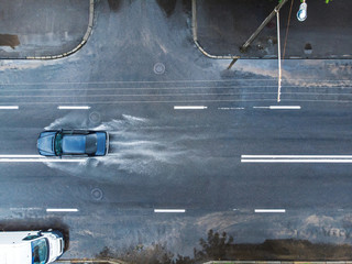 Wall Mural - black car splashes through large puddle on flooded street. aerial photo