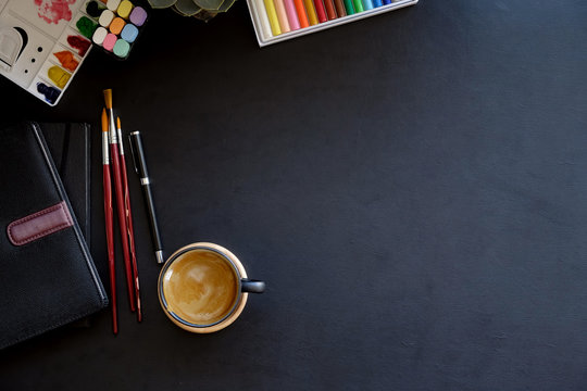 Artist workplace with creative craft tools on dark leather desk.