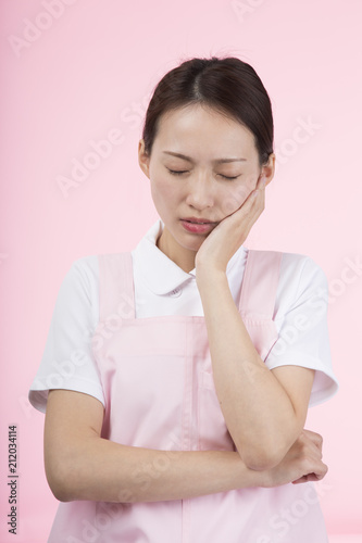 頬に手を当てて痛そうな顔をする白衣とエプロンを着た女性 Stock Photo Adobe Stock