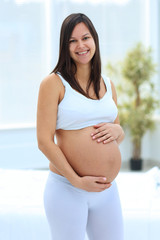 Wall Mural - portrait of young pregnant woman on a light background.