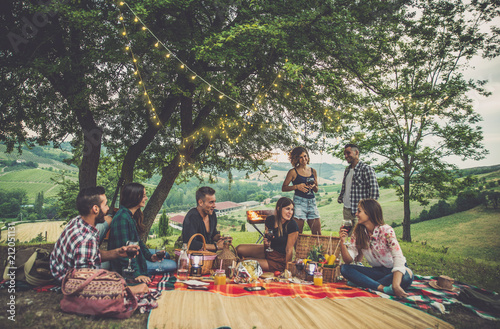 Fotografía Group of friends spending time making a picnic and a barbeque