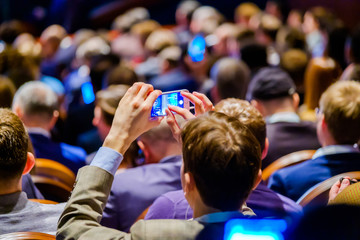 Wall Mural - man takes a picture of the presentation at the conference hall using smartphone