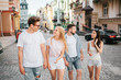 © estradaanton - Two couples are walking on the street. Guy in glasses and blonde girl is walking in front. They are looking at each other and smiling. Another couple is walking behind.