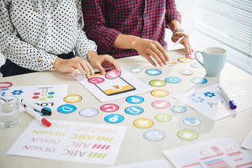 Wall Mural - faceless shot of man and woman creating new web application and working with colorful icons for desi