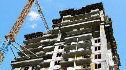 Construction builsing against blue sky. Crane near building. Construction site.