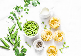 Mediterranean style healthy food ingredients for cooking lunch - fettuccine pasta, fresh green peas, cream, spices on a light background, top view. Flat lay