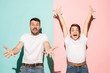 © master1305 - Closeup portrait of young couple, man, woman. One being excited happy smiling, other serious, concerned, unhappy on pink and blue background. Emotion contrasts