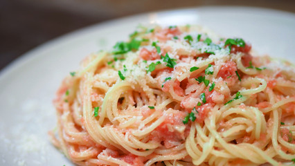 Close-up image of spaghetti sauce tarako which made from fresh cod fish in Japan and mixed with Thai coriander on the top of white plate and famous italian-japanese menu dish in Thailand restaurant