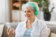 © Syda Productions - technology, people and lifestyle concept - happy senior woman in headphones and smartphone listening to music at home