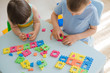 A boy and a girl collect a soft puzzle at the table. Brother and sister have fun playing together in the room. Preschool children and educational toys