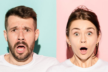 Wall Mural - Closeup portrait of young couple, man, woman. One being excited happy smiling, other serious, concerned, unhappy on pink and blue background. Emotion contrasts