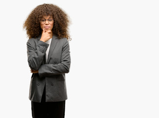 Poster - African american business woman wearing glasses looking confident at the camera with smile with crossed arms and hand raised on chin. Thinking positive.