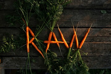 Word raw shaped from fresh carrots. Raw written with freshly picked vegetables carrots.