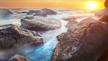 Colorful Sunset Over Ocean With Big Stones Close Up. Bright Color. Dramatic Nature Landscape. Holidays, Travel, Vacation Background. Water Long Exposure Movement. 4K Slow Motion Time Lapse Parallax