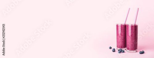 Fotografía Two glasses of blueberries smoothie with straws on pink background