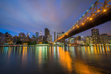 Fototapeta Miasta - The Queensboro Bridge at night, seen from Roosevelt Island in New York City.
