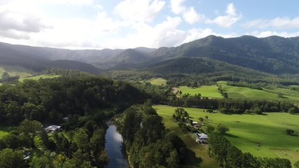 Wall Mural - Bellinger river and valley with developed agriculture on riverbanks towards woods covered mountains of Dorrigo National Park.
