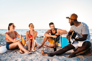 happy young multiethnic friends spending time together on sandy beach